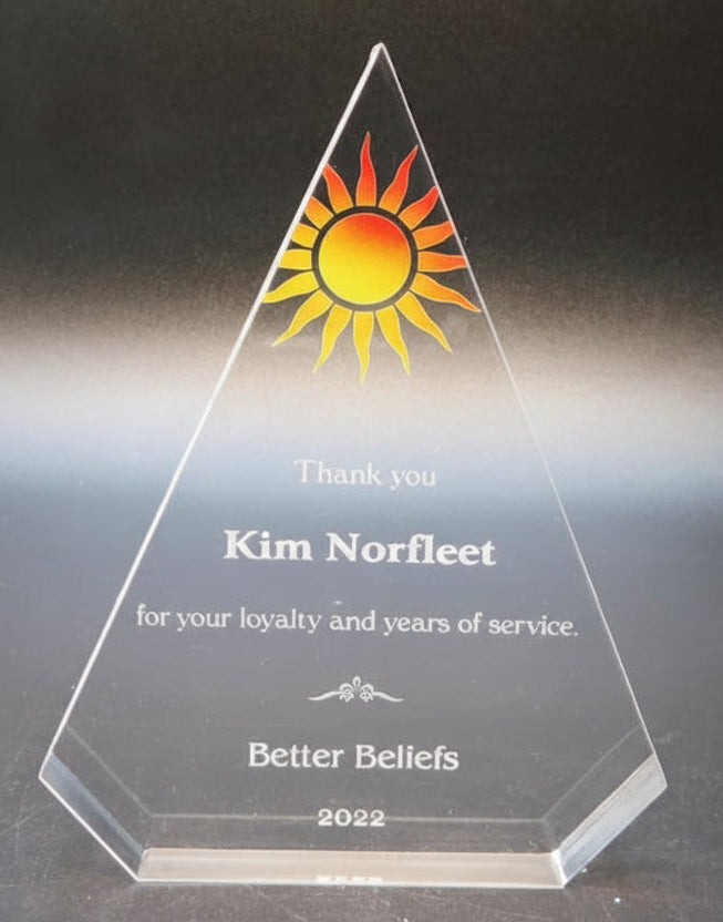 Clear triangular award with engraved text on a dark background
