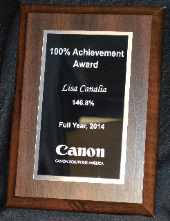 Plaque with '100% Achievement Award' from Canon on a dark fabric background