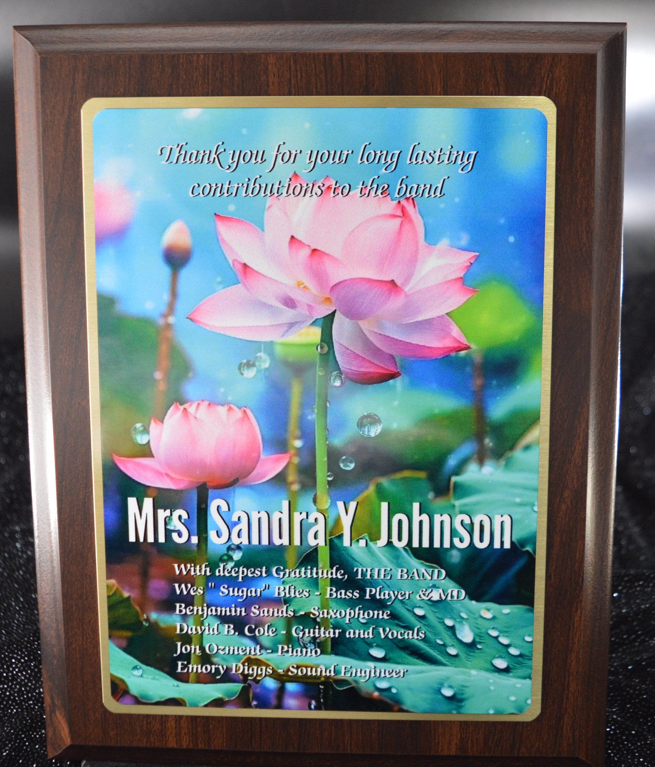 Decorative plaque with pink lotus design and engraved text on a reflective surface