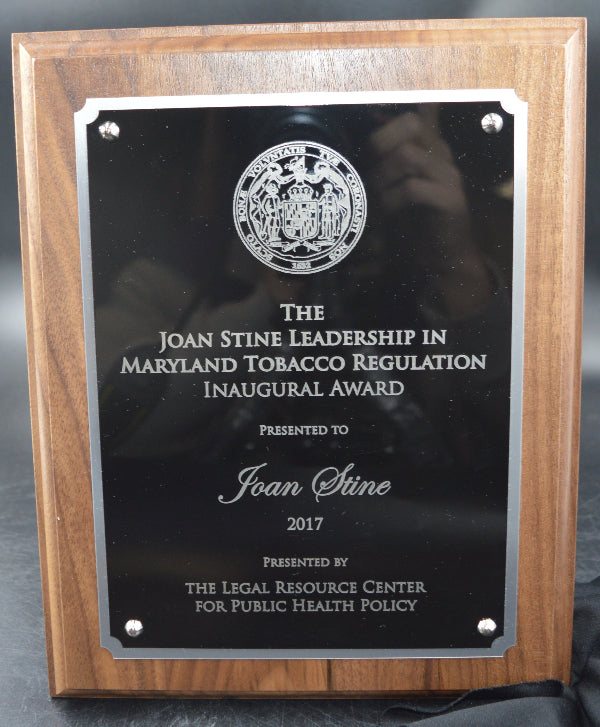 Wooden plaque with a black certificate on a gray surface