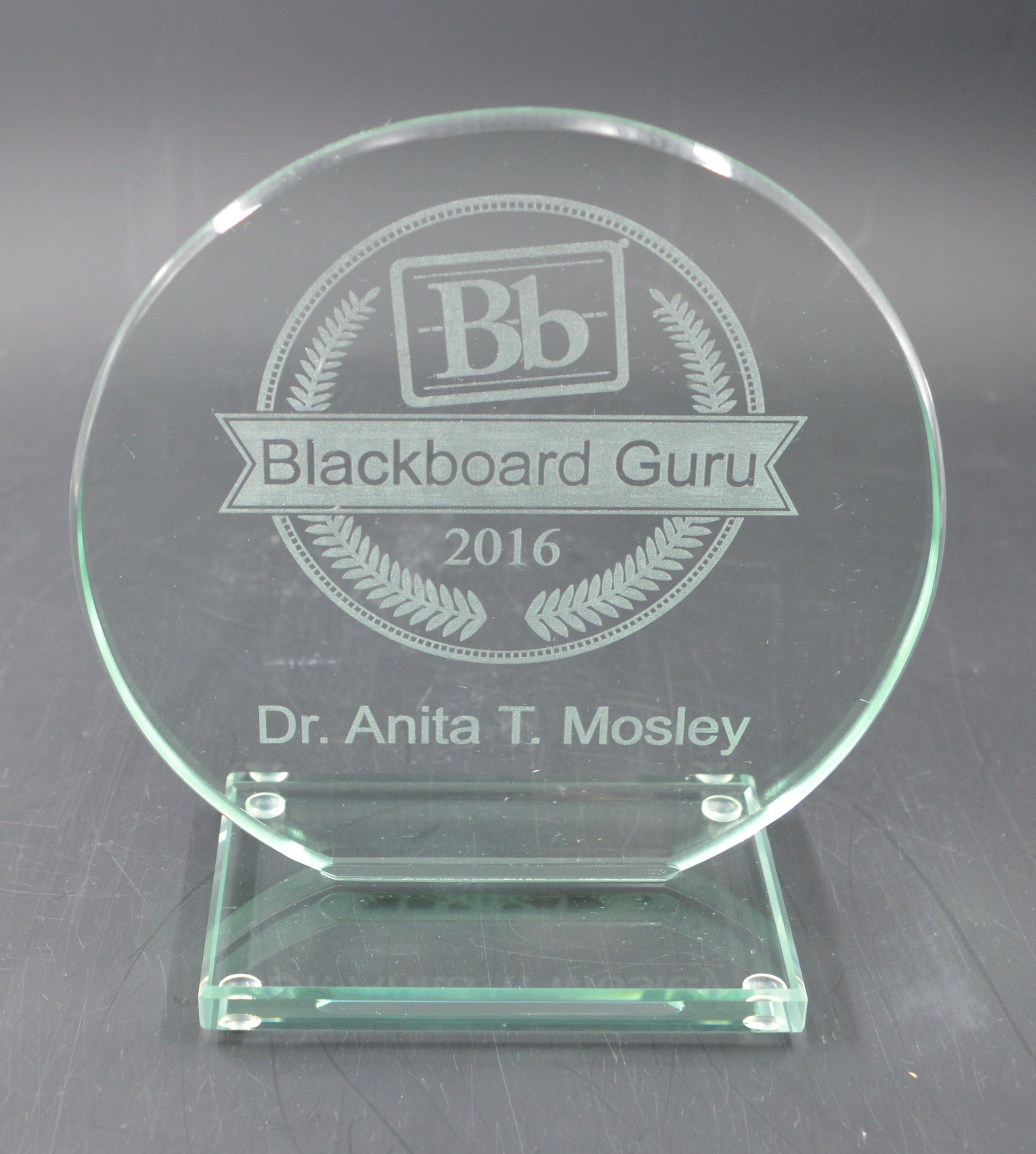Glass award with engraved text on a reflective surface