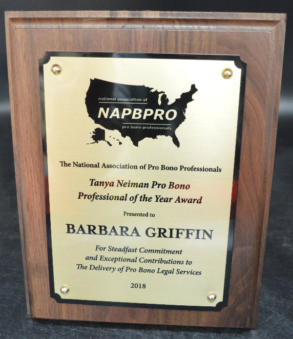 Wooden plaque with NAPBBPRO award for Barbara Griffin on a dark surface.