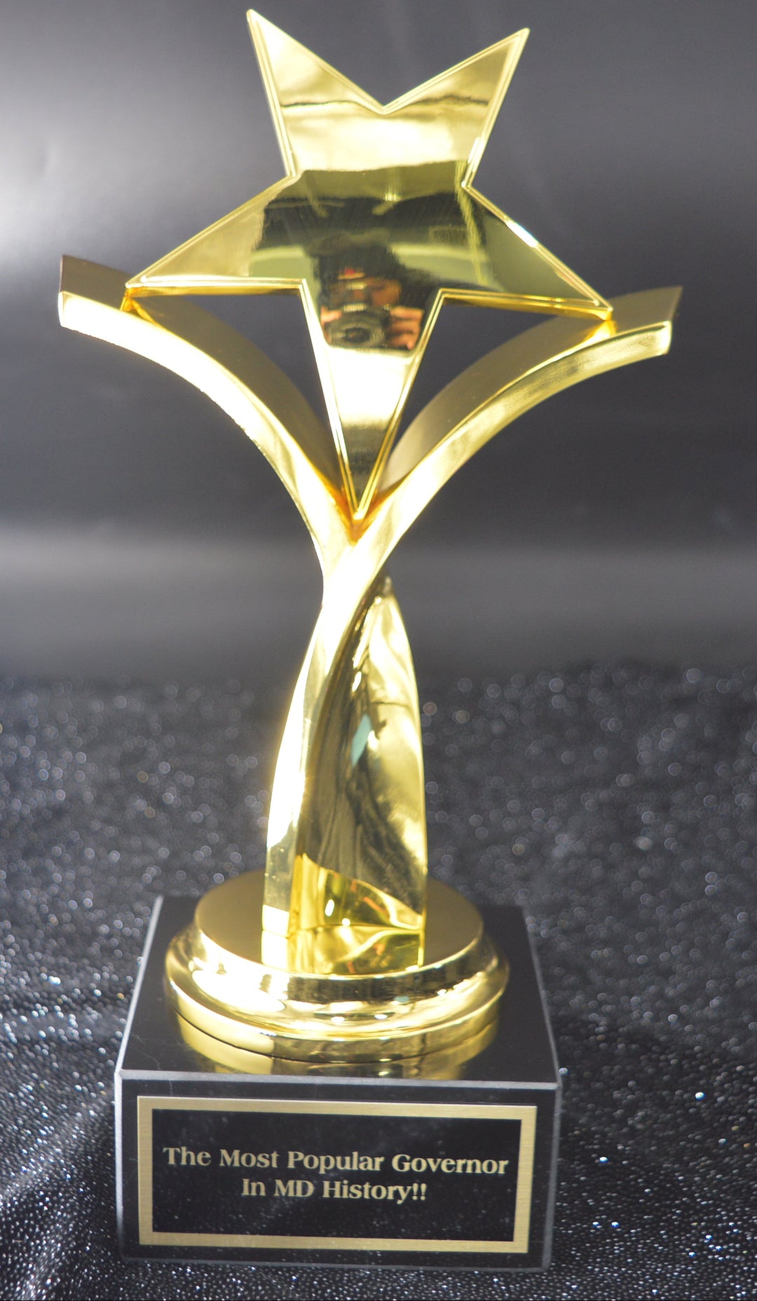 Gold star-shaped trophy on a black glittery surface