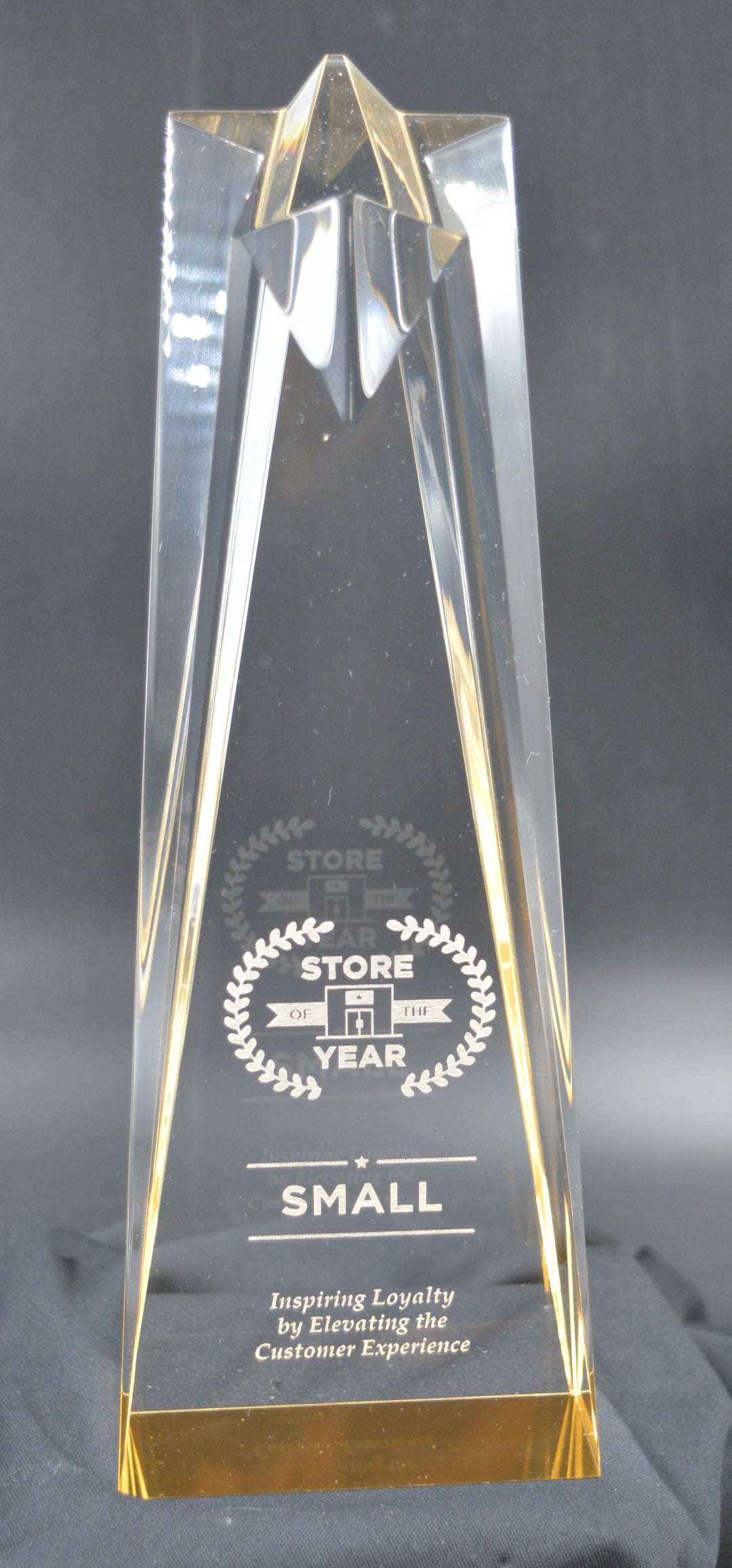 Tall, clear ACRYLIC award with engraved text on a dark gray background