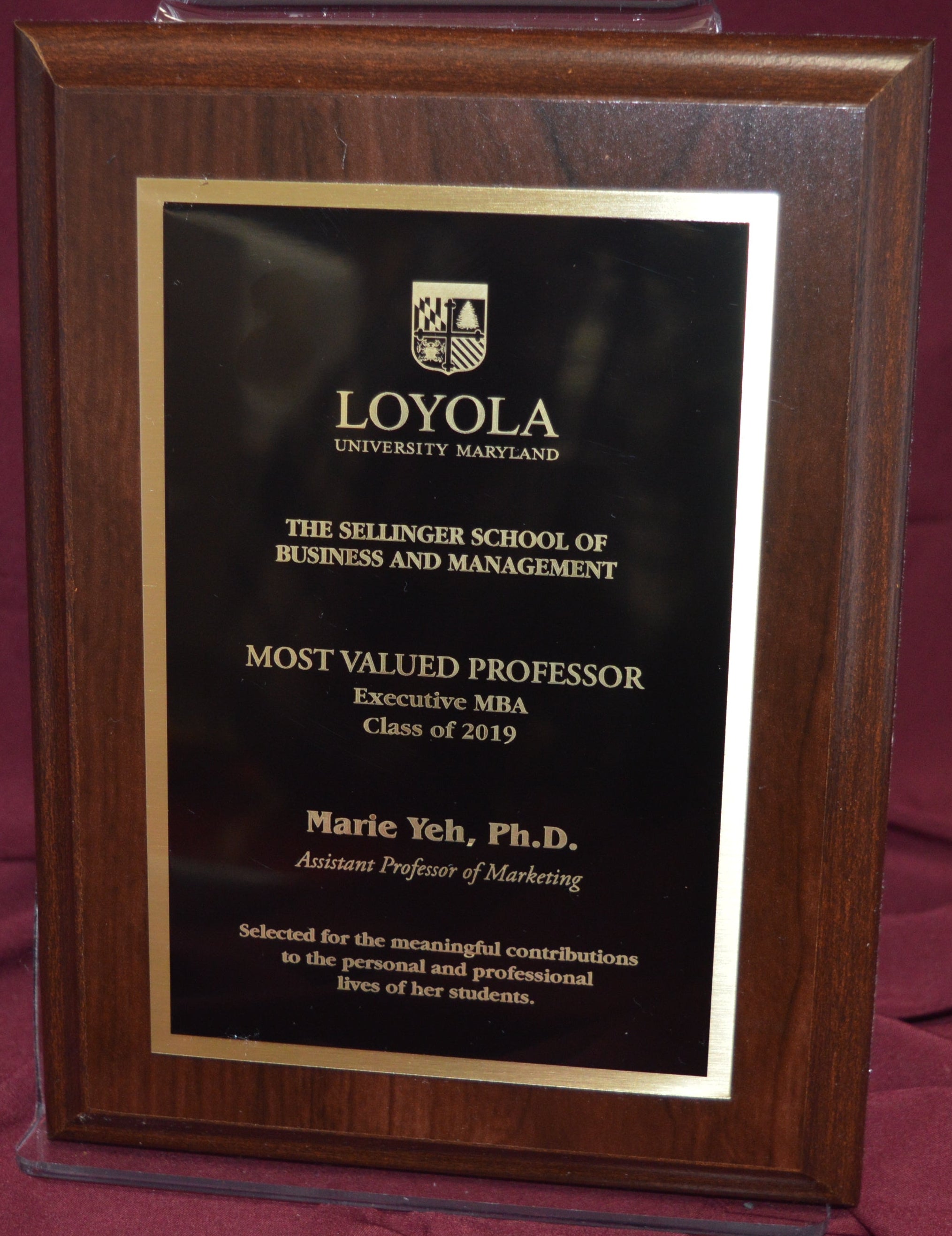 Wooden plaque with Loyola University recognition on a maroon fabric background