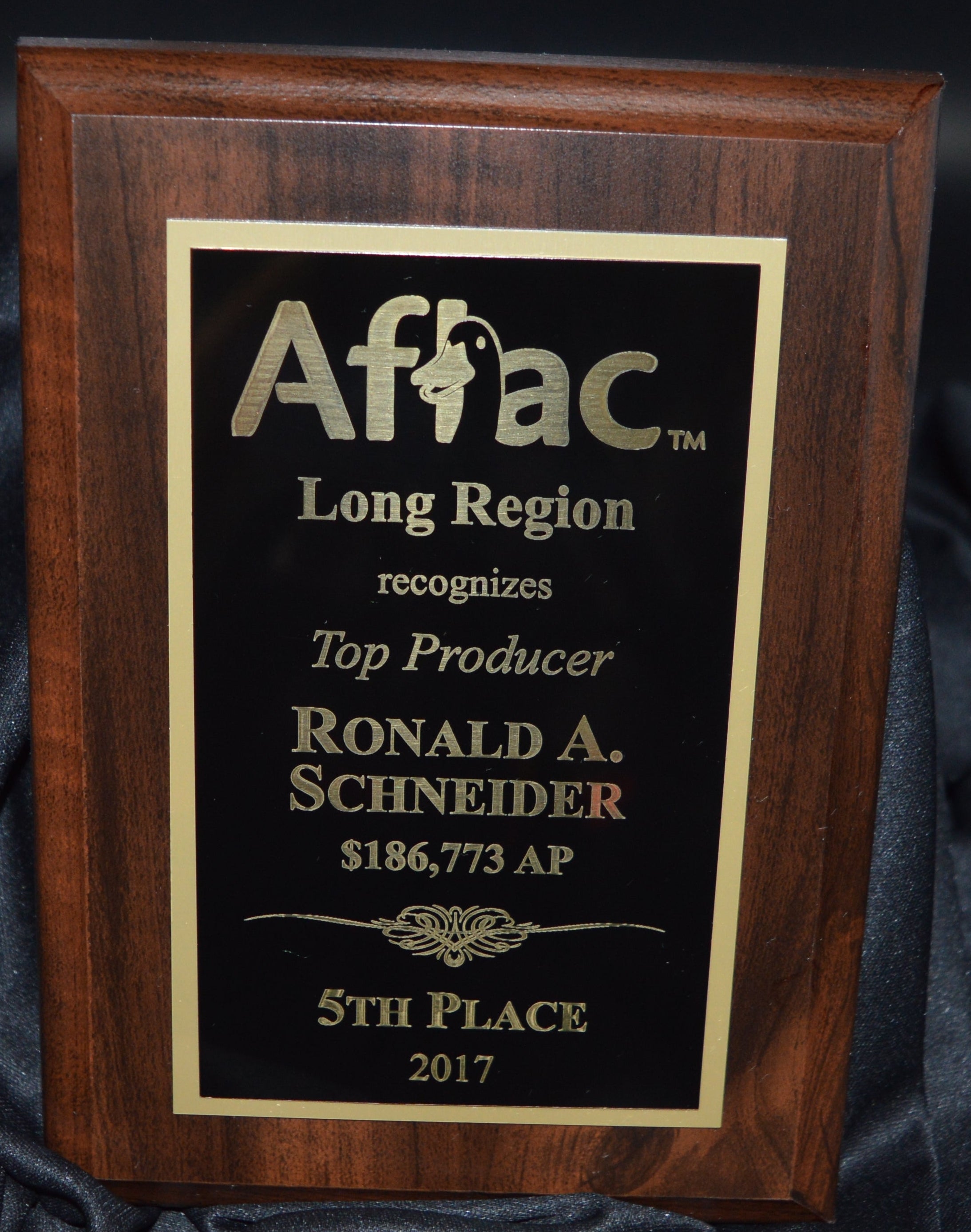 Wooden plaque with gold text on a black fabric background