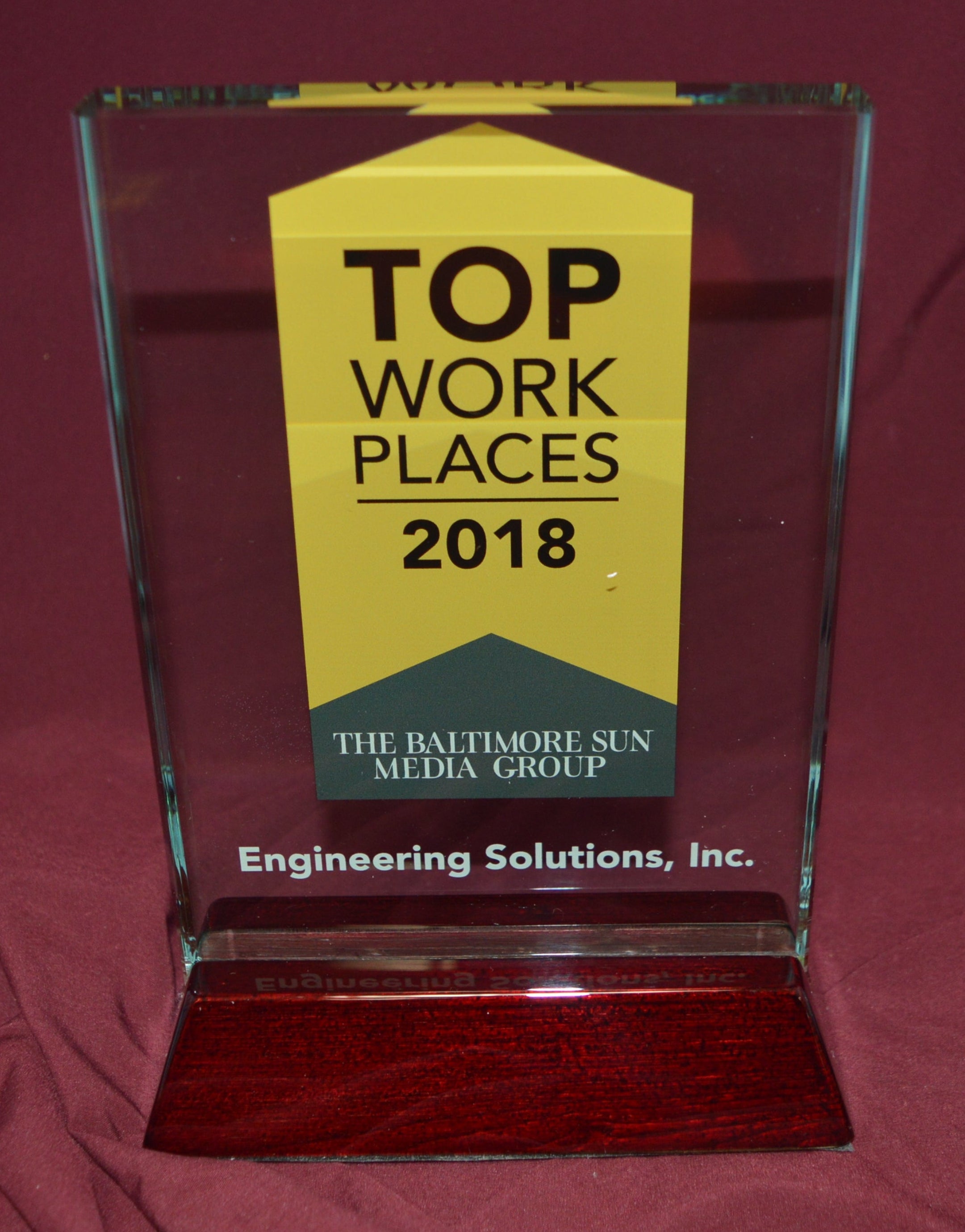 Awards plaque for 'Top Workplaces 2018' on a red fabric background
