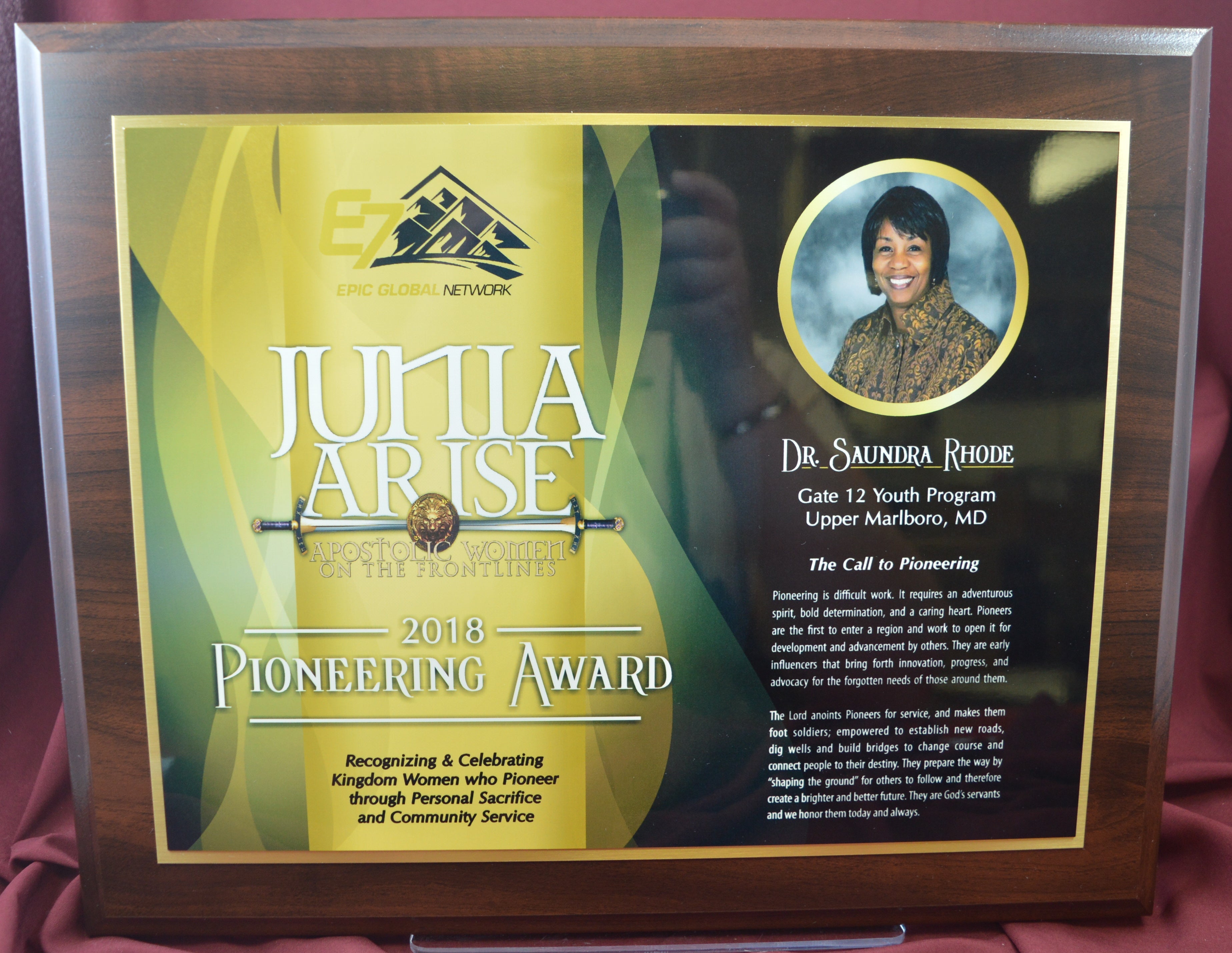 Plaque with 'Junia Arose' 2014 Pioneering Award on a red background