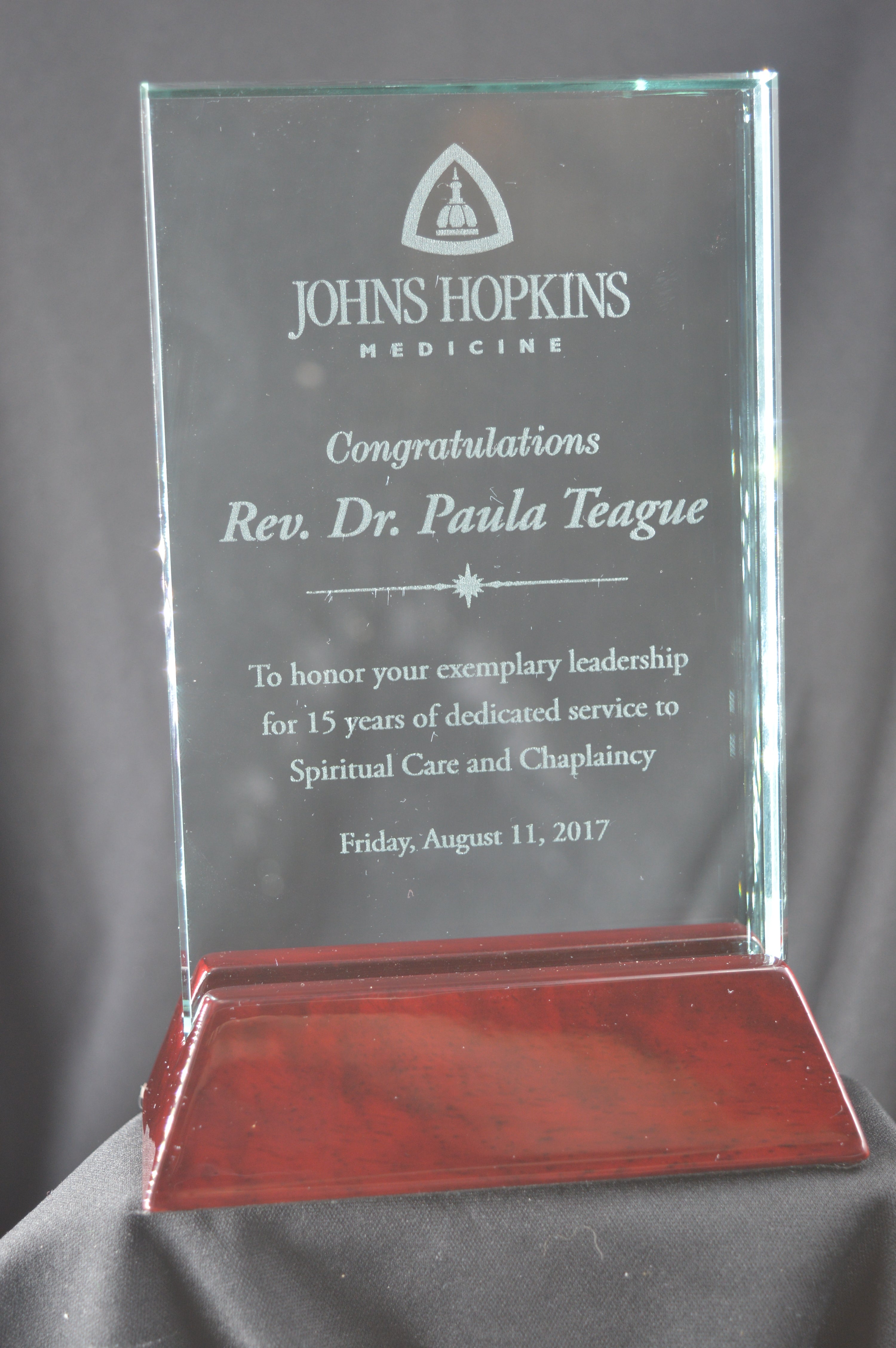 Glass award with engraved text on a dark background