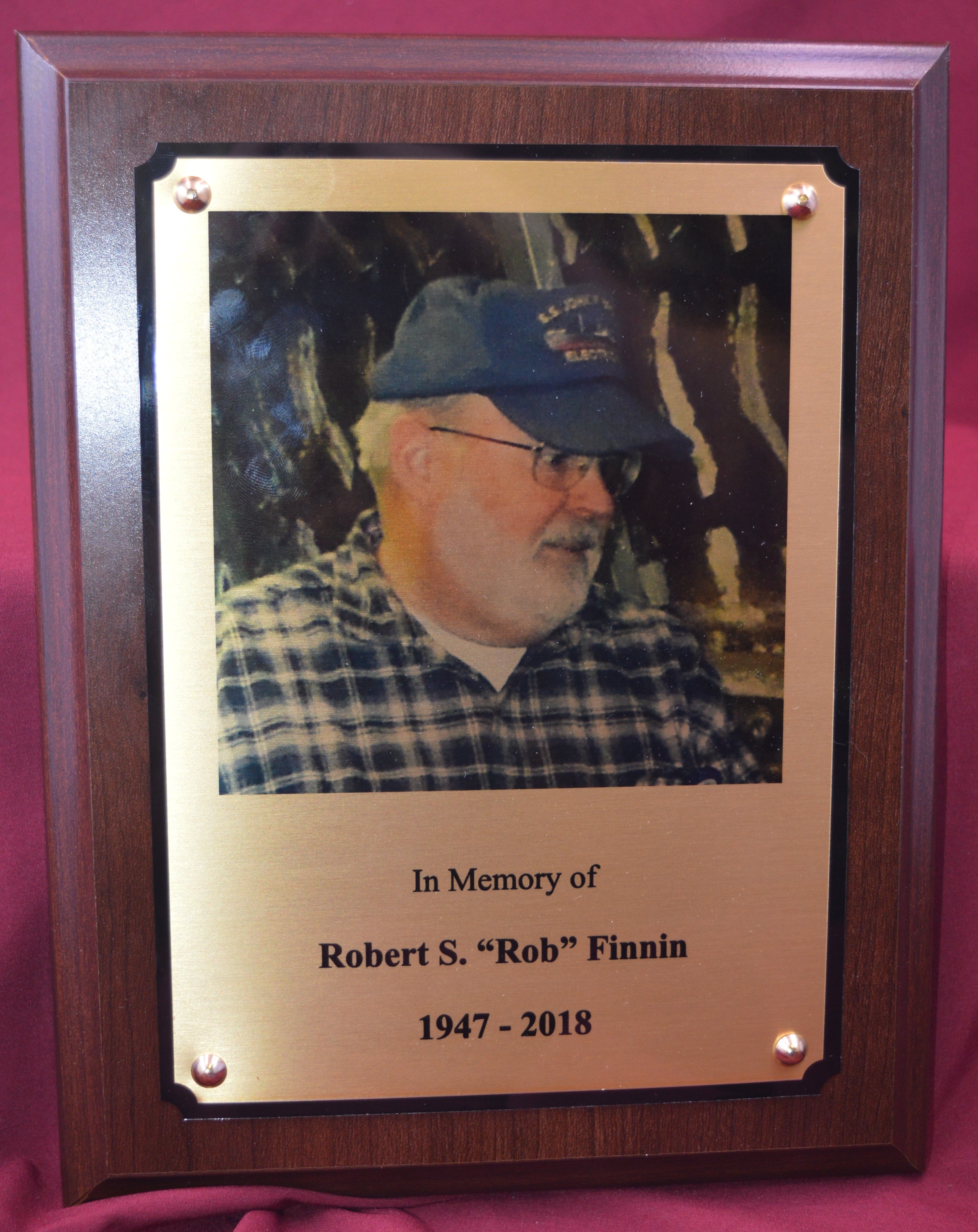 Memorial plaque with a photo of a man and engraved text on a pink background