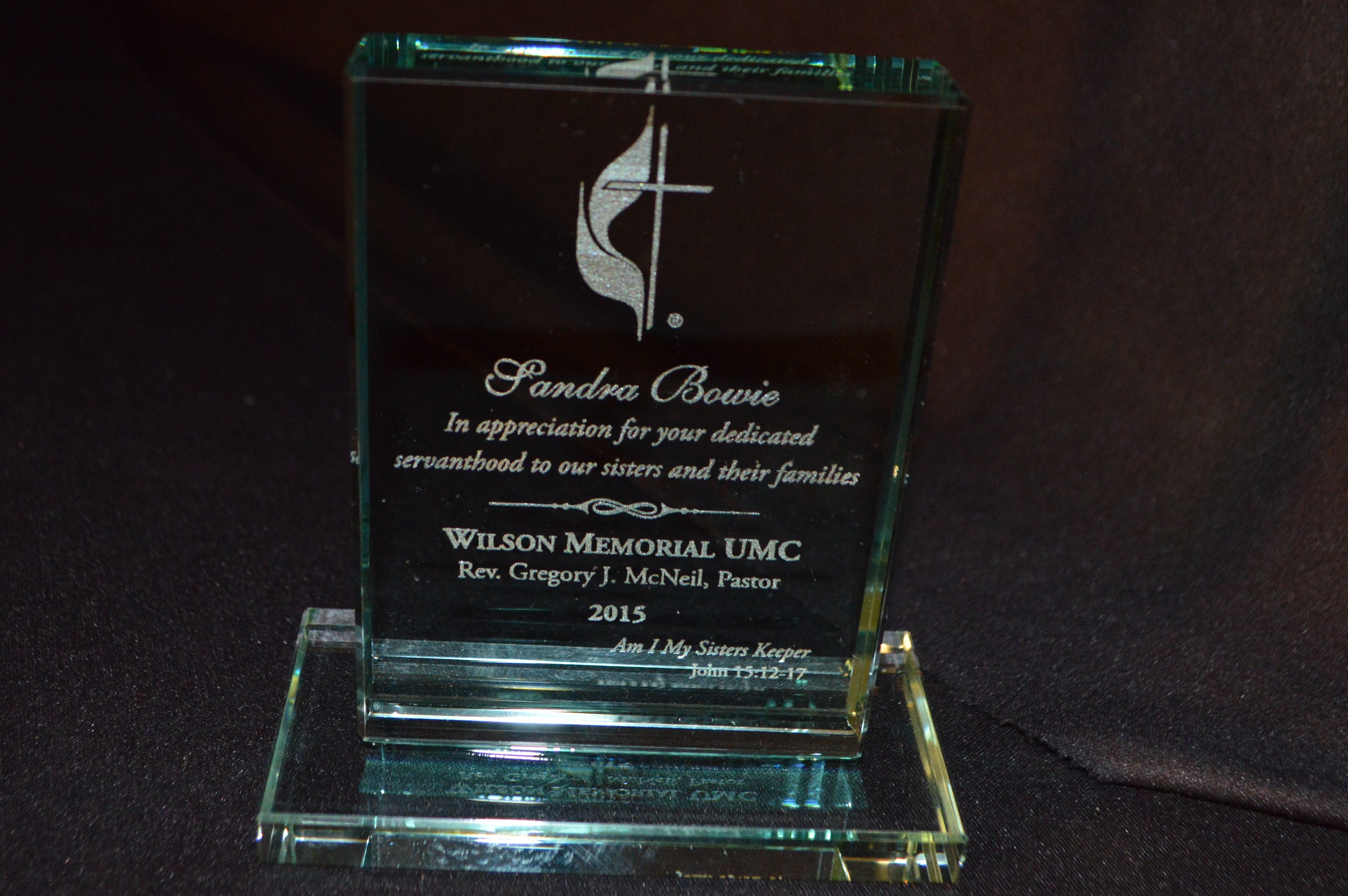 Glass award with engraved text on a dark background